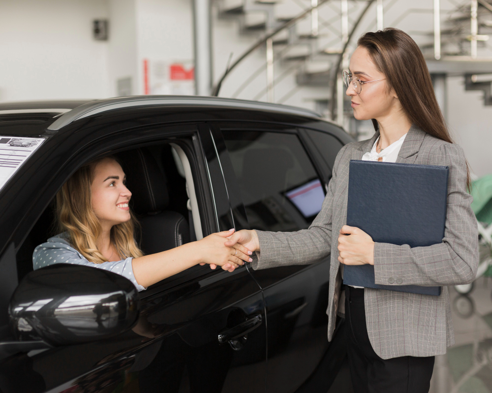 A woman buying a new car with a provisional licence from a saleswoman